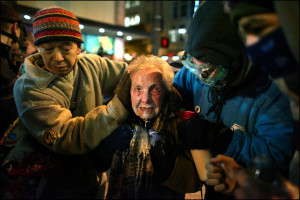 Seattle activist Dorli Rainey, 84, is helped by fellow Occupy Seattle protestors after being hit with pepper spray Tuesday, November 15, 2011. After asking protestors to move to the sidewalk, police doused protestors with what Rainey later described as "a fountain of pepper spray." Other protesters splashed a milky-solution in Rainey's face to reduce the sting of the chemical irritant. The incident sparked international outrage, a review of the department's response to the protest, and an apology from Seattle Mayor Mike McGinn.